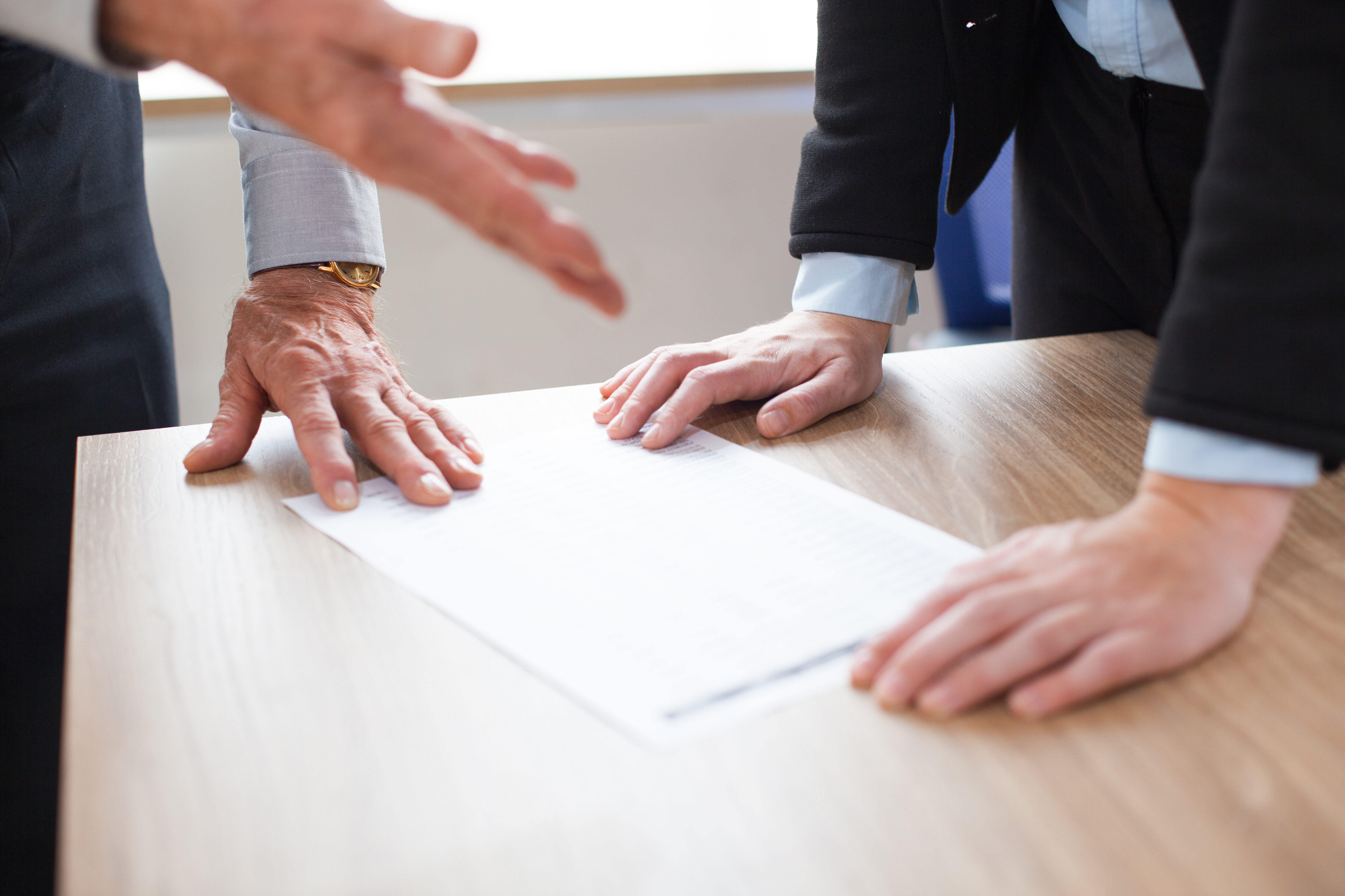 Close-up of two people discussing legal document on a table
