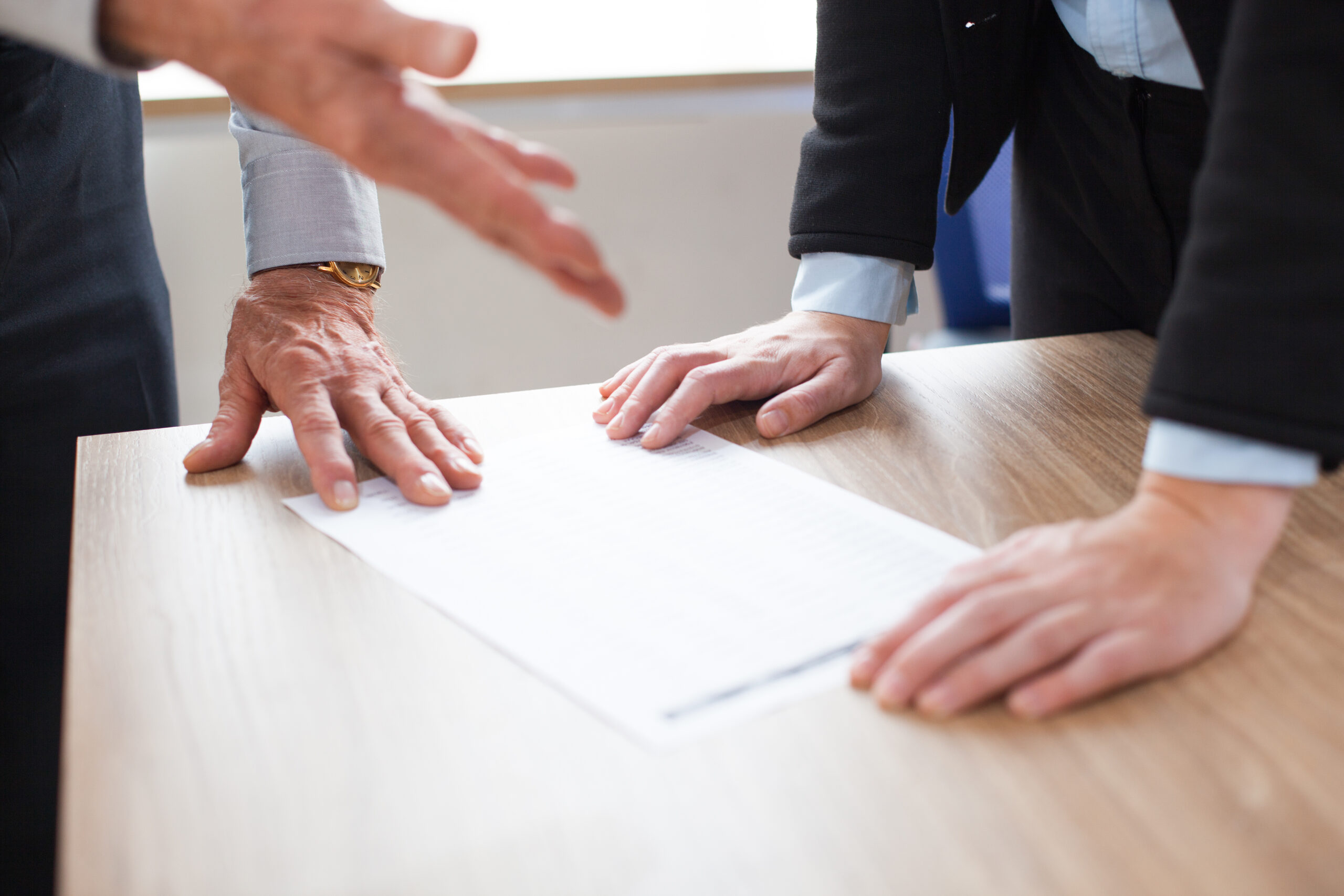 Close-up of two people discussing legal document on a table
